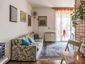 A living room with a sofa, a table, a radiator, and a window with curtains. - Casa di Flavia by Interhome (Riva Ligure)