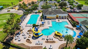 Um resort com uma grande piscina, um toboágua e quadra de tênis.