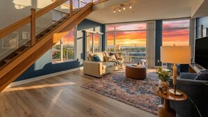 A modern living room with a staircase, large windows, and a city view. - Modern 1BR Penthouse  Heart of CLE Views (Cleveland)