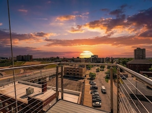 Sonnenuntergangsblick von einem Hochhaus mit Parkplatz und Stadtlandschaft im Vordergrund.