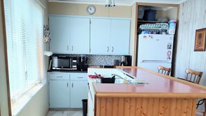 Eine Küche mit weißen Schränken, einer Holzinsel, einer Uhr und einem Kühlschrank.