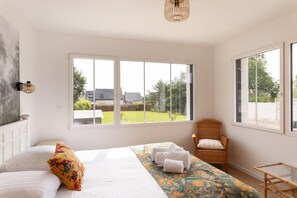 A bedroom with a large bed, a chair, and a view of the outdoors. - La Brise - À moins d’1 km de la plage (Fréhel)