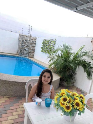 A person seated at a table with a pool in the background.