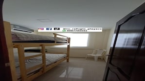 Habitación con literas, una silla blanca, una puerta y una ventana.