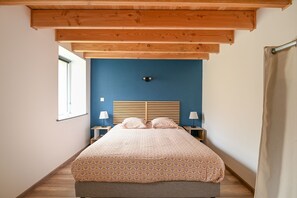 A bedroom with a bed, wooden headboard, bedside lamps, and a window.