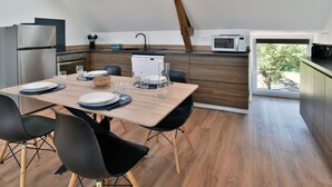 Une cuisine moderne avec un coin repas, comprenant une table en bois, des chaises noires et une lucarne.