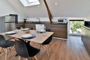 Eine moderne Küche mit Essbereich, ausgestattet mit einem Holztisch, schwarzen Stühlen und einem Oberlicht.