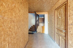 A hallway with wooden walls and a tiled floor, leading to a staircase and a wooden door. - La Motte Forte - Jolie maison en centre médiéval (Arnay-le-Duc)