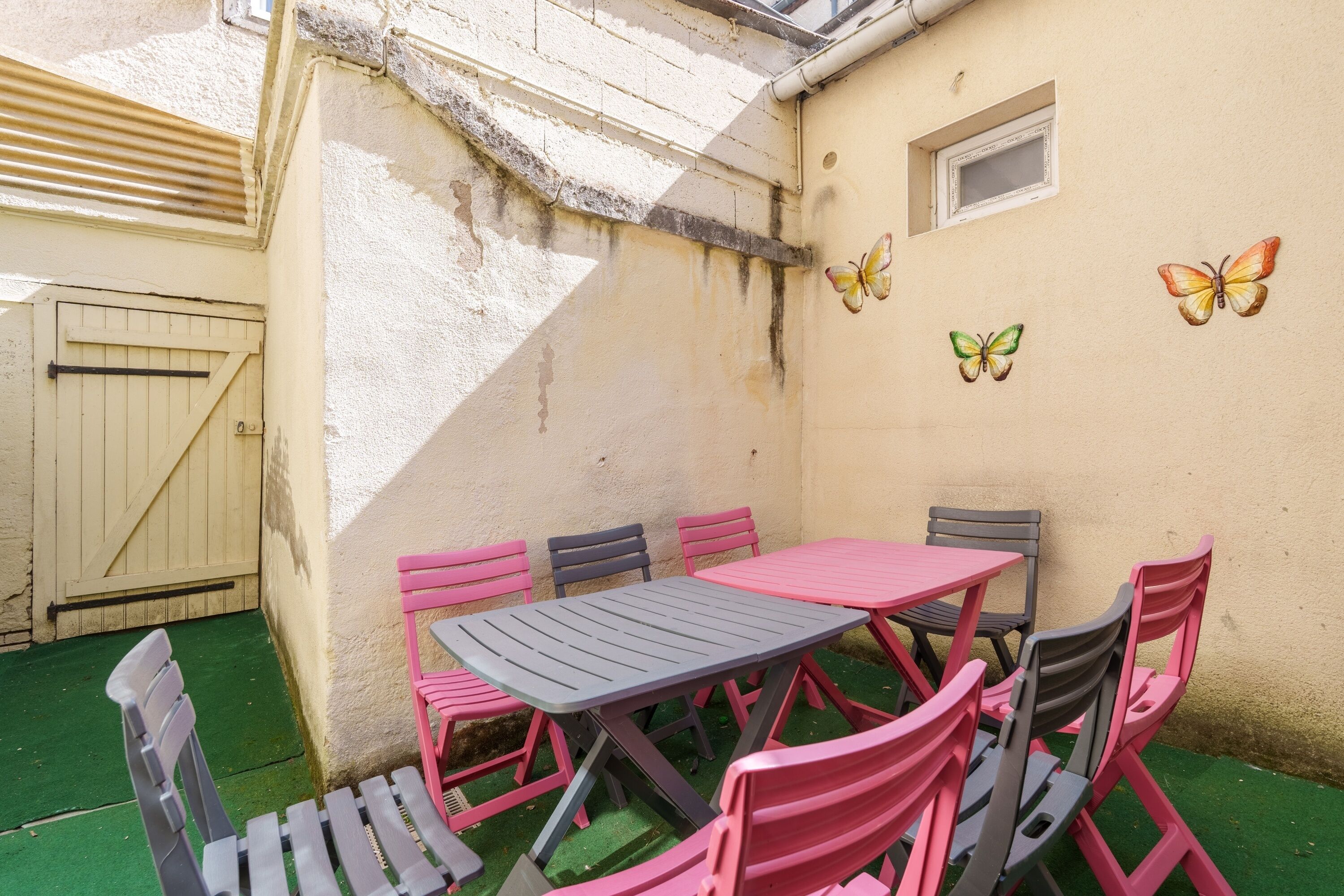 A patio with a table and chairs, a window, and a door.