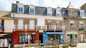 A row of buildings with a pharmacy, a creperie, and a restaurant. - Grain de corail - Bel appt à 2 pas de la plage (Pléneuf-Val-André)