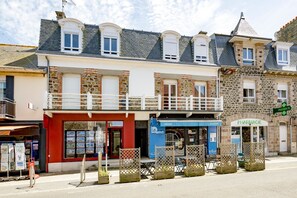 A row of buildings with a pharmacy, a creperie, and a restaurant. - Grain de corail - Bel appt à 2 pas de la plage (Pléneuf-Val-André)