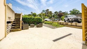 A parking area with a concrete floor, a staircase, and a gate. - Grain de corail - Bel appt à 2 pas de la plage (Pléneuf-Val-André)