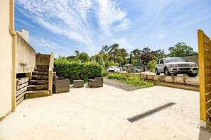 A parking area with a concrete floor, a staircase, and a gate. - Grain de corail - Bel appt à 2 pas de la plage (Pléneuf-Val-André)