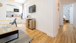 A modern kitchen with white cabinets, a microwave, and a TV mounted on the wall. - Grain de corail - Bel appt à 2 pas de la plage (Pléneuf-Val-André)