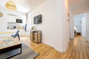 A modern kitchen with white cabinets, a microwave, and a TV mounted on the wall. - Grain de corail - Bel appt à 2 pas de la plage (Pléneuf-Val-André)