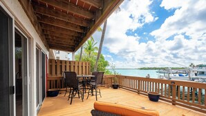 A wooden deck with outdoor furniture, a view of the water, and a boat docked in the background. - SALTWATER SOUL - 2 Bedroom / 2.5 Bathroom Waterfront Townhome W/ Shared Pool (Key West)