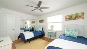 A bedroom with two beds, a ceiling fan, a window with blinds, and artwork on the walls. - SALTWATER SOUL - 2 Bedroom / 2.5 Bathroom Waterfront Townhome W/ Shared Pool (Key West)