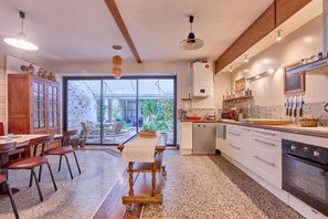 Eine moderne Küche mit Essbereich, großen Fenstern und Blick auf Grünfläche.