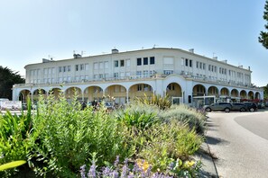 A large, multi-story building with a central courtyard, surrounded by lush greenery. - Le Palais des Arcades - Studio 100m de la Plage (Fréhel)