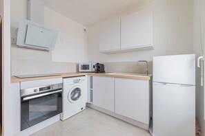 A modern kitchen with a dishwasher, oven, microwave, and refrigerator. - Les Voiles de Nacre - Appt à 100m de la plage (Courseulles-sur-Mer)