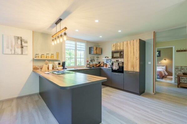 A modern kitchen with a central island, built-in appliances, and a large window.