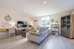 A modern living room with a sofa, TV, desk, and bookshelf.