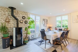 A dining area with a brick wall, a black stove, potted plants, and a table set for two.