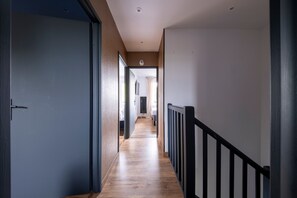 A hallway with wooden flooring, a black railing, and a ceiling light. - La Villa Rosa - Avec Piscine Privée (Toulouse)