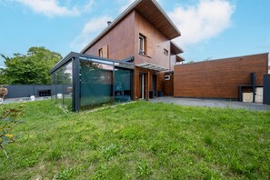 A modern house with a glass conservatory, wooden exterior, and a well-maintained lawn. - La Villa Rosa - Avec Piscine Privée (Toulouse)