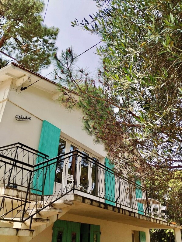 Ein Gebäude mit einer Treppe, einem Schild mit der Aufschrift 'KERIBA' und einem Balkon mit Geländer.