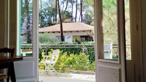 Une porte ouverte donnant sur un balcon avec vue sur des arbres et un immeuble.