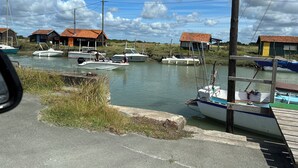 Un port de plaisance avec des bateaux amarrés, une jetée en bois et, au fond, des maisons aux toits rouges.