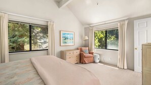 Een slaapkamer met een bed, een kaptafel, een stoel en een raam met gordijnen.