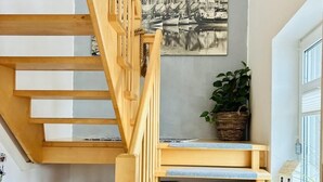 A wooden staircase with a view of a harbor painting above. - Vacation apartment DE VRIESenkoje (Südbrookmerland)