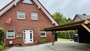 Une maison à deux étages, construite en briques, avec une porte blanche, des fenêtres et une antenne parabolique.