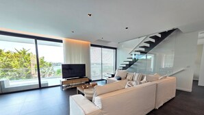 Una sala de estar moderna con un sofá grande, un televisor de pantalla plana y una escalera.