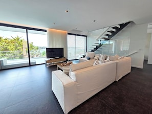 Ein modernes Wohnzimmer mit einer großen Couch, einem Flachbildfernseher und einer Treppe.