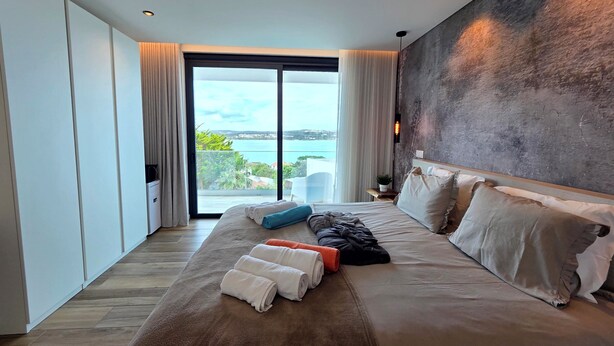 Una habitación de hotel moderna con una cama grande, vista al mar y un diseño minimalista.
