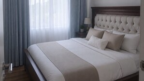 Ein Schlafzimmer mit einem großen Bett, einem Nachttisch mit Lampe und einem Fenster mit Vorhängen.
