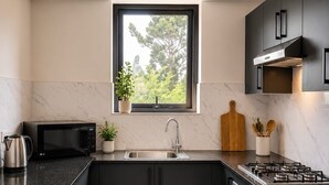 Eine moderne Küche mit Einbau-Mikrowelle, Spüle, Herd und dunklen Schränken.