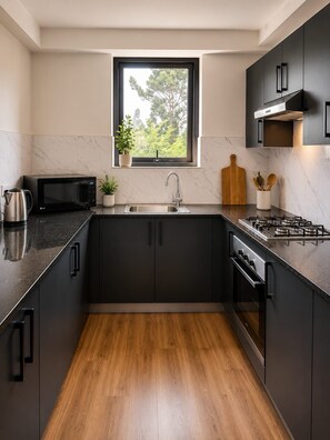 Eine moderne Küche mit Einbau-Mikrowelle, Spüle, Herd und dunklen Schränken.