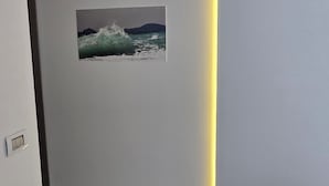 En modern inredning med ett försänkt tak, en tavla med ett vågmotiv som hänger på väggen och ett klinkergolv.