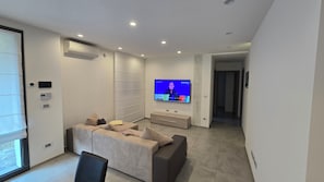 Una sala de estar moderna con una televisión de pantalla plana, un sofá, una mesa de centro y estanterías empotradas.