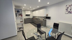 Une cuisine moderne avec une table à manger en verre, des placards intégrés et un radiateur blanc.
