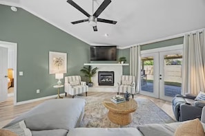 A living room with a ceiling fan, two armchairs, a sofa, a coffee table, and a fireplace.