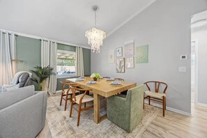 A dining area with a wooden table, chairs, a chandelier, and artwork on the walls.
