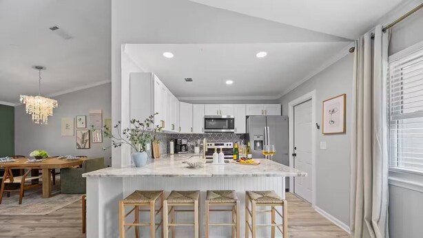 A modern kitchen with white cabinets, a marble island, and bar stools.