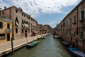 Ein Kanal mit Booten, historischen Gebäuden und wolkenlosem Himmel.