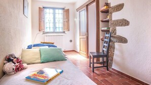 A bedroom with a bed, pillows, a chair, a window, and a wall with a unique design. - COUNTRY HOUSE (Greve in chianti)