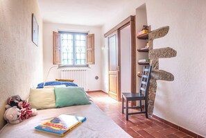 A bedroom with a bed, pillows, a chair, a window, and a wall with a unique design. - COUNTRY HOUSE (Greve in chianti)